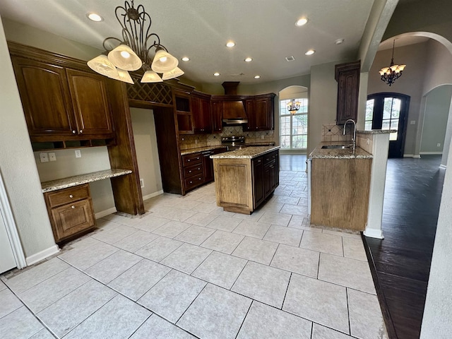 305 Tyler Dr, Bridge City, TX 77630 - kitchen featuring arched walkways, a sink, a chandelier, light stone countertops, and tasteful backsplash