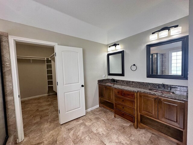 305 Tyler Dr, Bridge City, TX 77630 - bathroom with a walk in closet, baseboards, and double vanity
