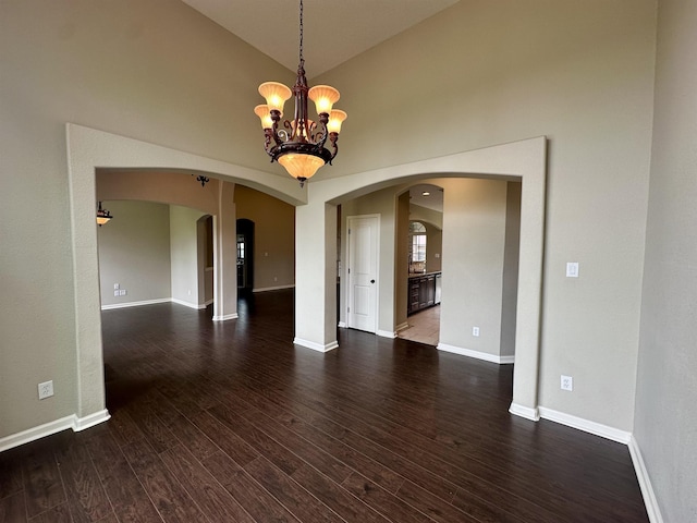 305 Tyler Dr, Bridge City, TX 77630 - empty room featuring arched walkways, a chandelier, dark wood-type flooring, baseboards, and high vaulted ceiling