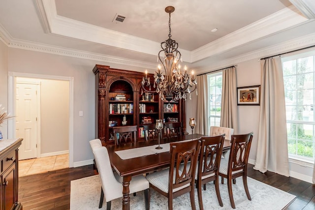 dining area featuring a notable chandelier, dark hardwood / wood-style flooring, ornamental molding, and a tray ceiling