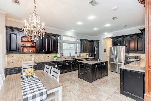 kitchen with pendant lighting, light tile patterned floors, appliances with stainless steel finishes, tasteful backsplash, and a kitchen island