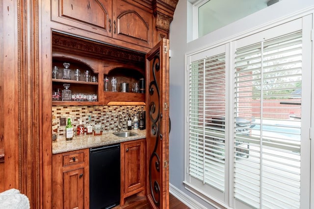 bar featuring backsplash, light stone counters, sink, and dark hardwood / wood-style floors