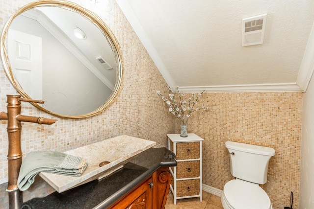 bathroom featuring tile patterned flooring, toilet, ornamental molding, and tile walls