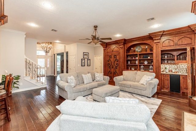 living room with dark hardwood / wood-style flooring, ceiling fan with notable chandelier, and ornamental molding