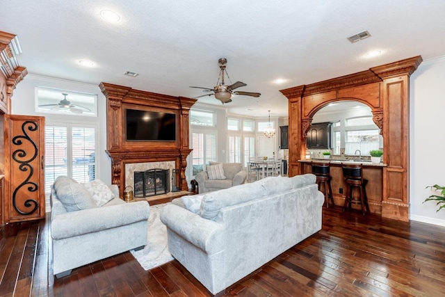 living room featuring sink, a fireplace, dark hardwood / wood-style floors, and ornamental molding