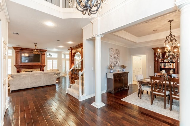 dining area featuring ornate columns, dark hardwood / wood-style floors, a notable chandelier, a tray ceiling, and ornamental molding