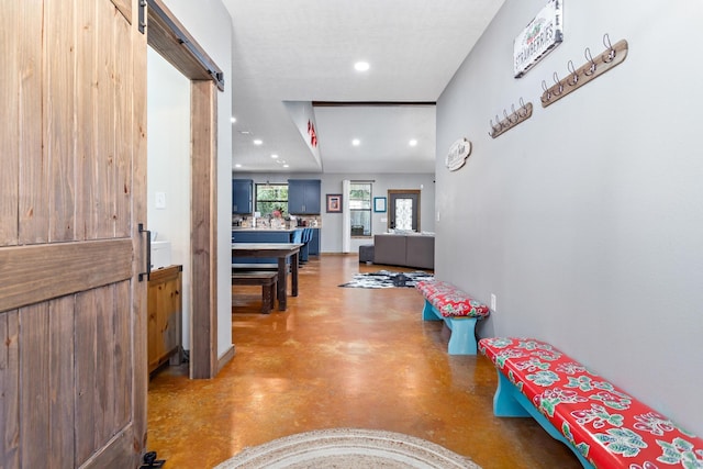 corridor with a barn door and concrete floors