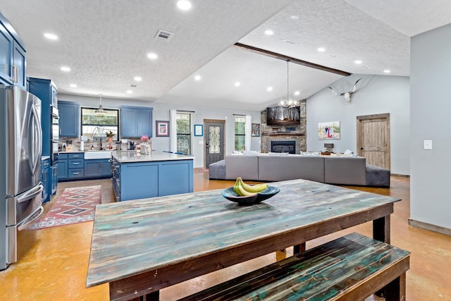 dining area with vaulted ceiling with beams, a fireplace, sink, and a textured ceiling