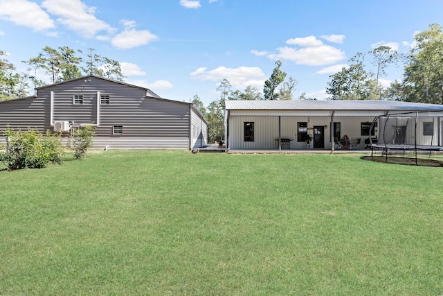 rear view of house with a yard and a trampoline