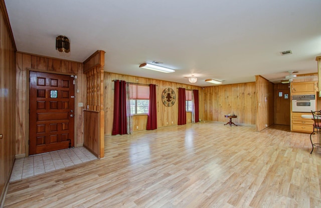 foyer with visible vents, light wood-type flooring, and wooden walls