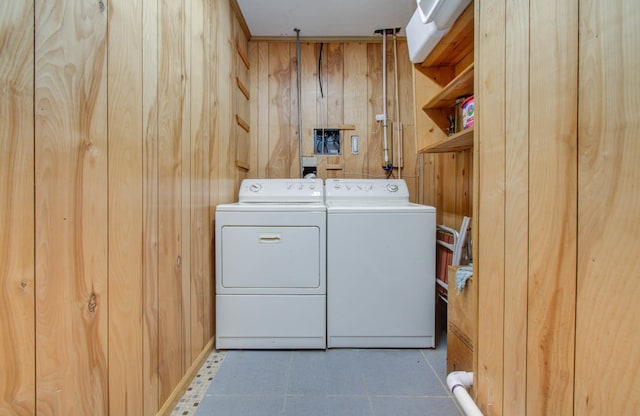 laundry area with tile patterned floors, laundry area, independent washer and dryer, and wooden walls