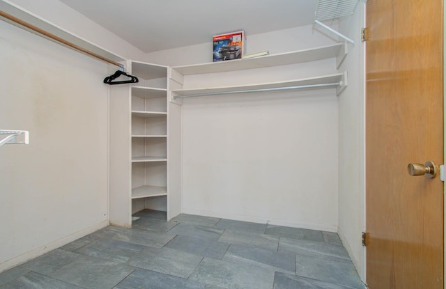 walk in closet featuring stone finish flooring