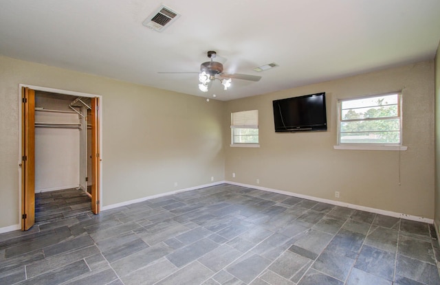 unfurnished bedroom with a ceiling fan, a spacious closet, baseboards, and visible vents