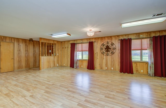 unfurnished room with visible vents, wood walls, and light wood-type flooring