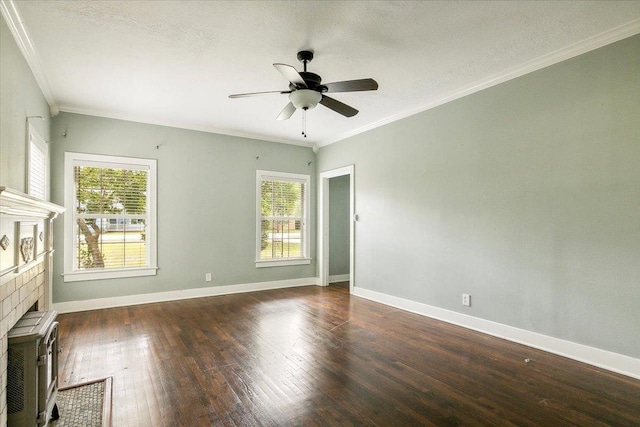 empty room featuring a tiled fireplace, crown molding, dark hardwood / wood-style floors, and a wealth of natural light