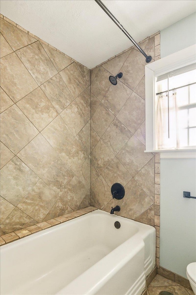 bathroom with tile patterned floors, toilet, and tiled shower / bath