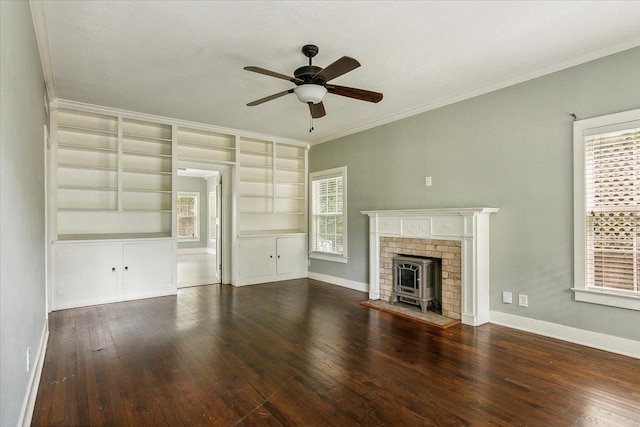 unfurnished living room with a wood stove, crown molding, built in shelves, dark hardwood / wood-style floors, and a wealth of natural light