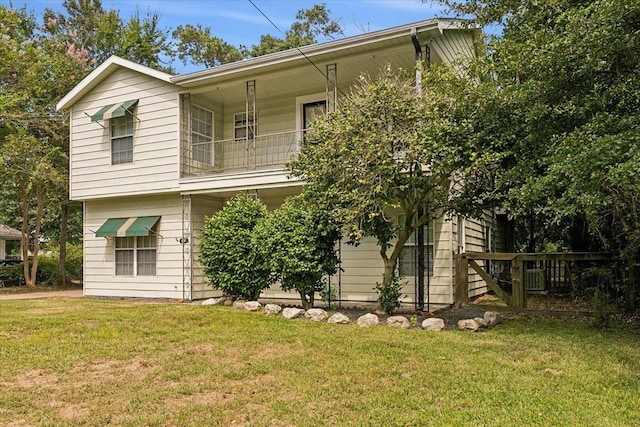 back of house with a yard and a balcony