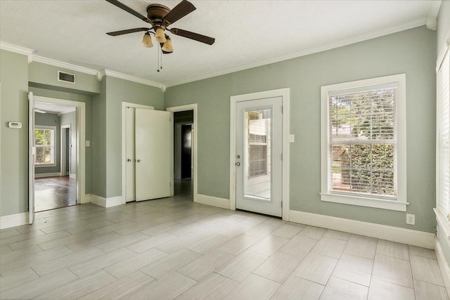 empty room with ceiling fan, crown molding, and a wealth of natural light