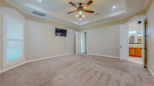 empty room featuring crown molding, light colored carpet, and a tray ceiling