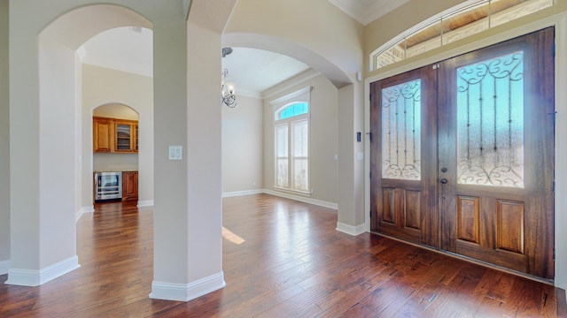 entrance foyer with dark hardwood / wood-style floors, ornamental molding, and beverage cooler