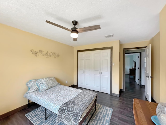 bedroom with ceiling fan, a closet, dark wood-type flooring, and a textured ceiling