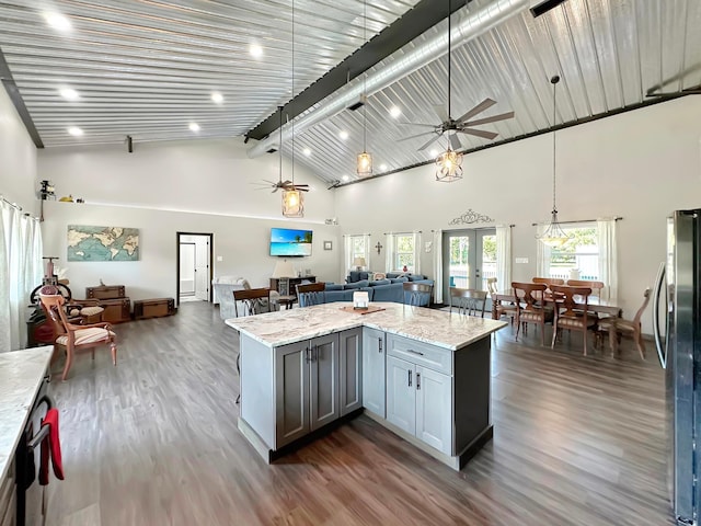 kitchen featuring french doors, dark hardwood / wood-style flooring, light stone counters, pendant lighting, and stainless steel refrigerator