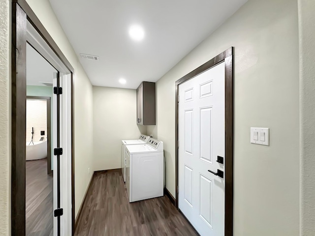 clothes washing area featuring cabinets, washing machine and dryer, and dark hardwood / wood-style floors