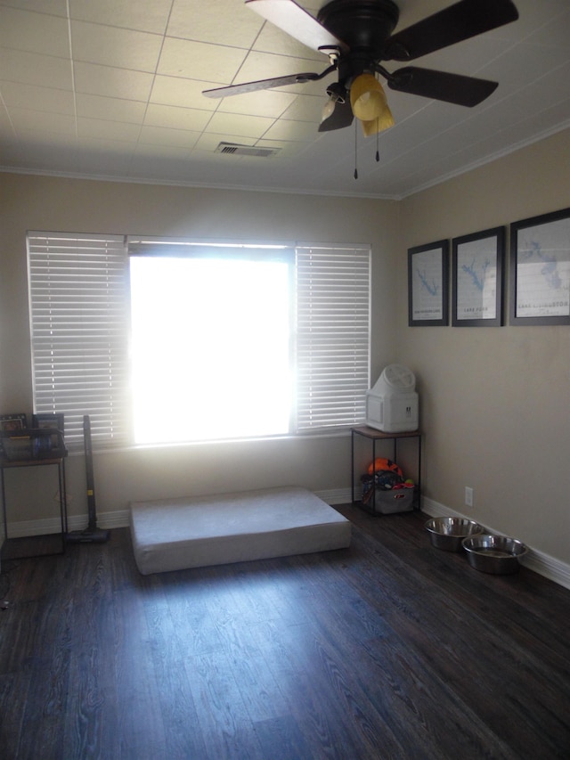 interior space with baseboards, crown molding, visible vents, and wood finished floors