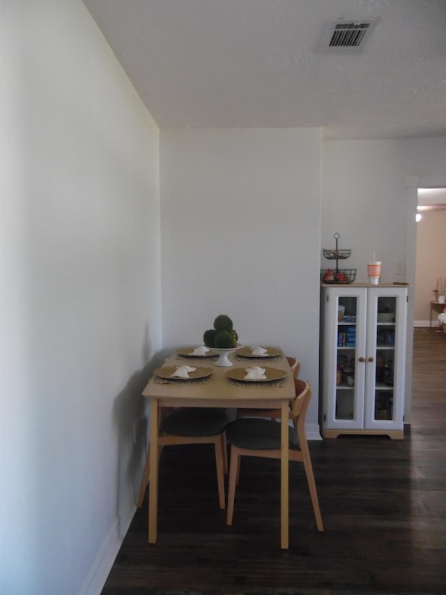 dining room with wood finished floors, visible vents, and baseboards