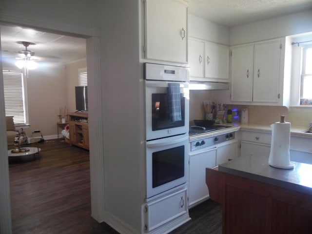 kitchen with dark wood-style floors, white double oven, cooktop, light countertops, and under cabinet range hood