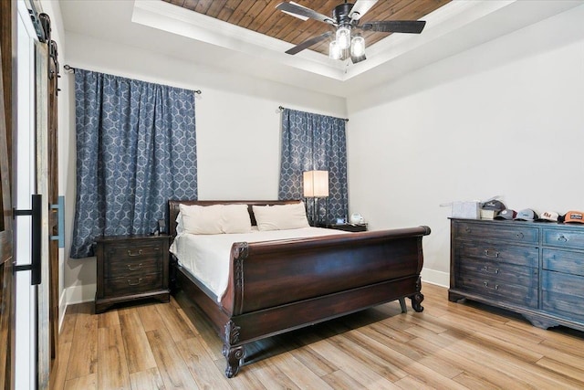 bedroom featuring ceiling fan, light wood-type flooring, ornamental molding, and a tray ceiling