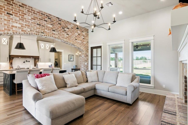 living room with a brick fireplace, brick wall, a notable chandelier, and hardwood / wood-style flooring