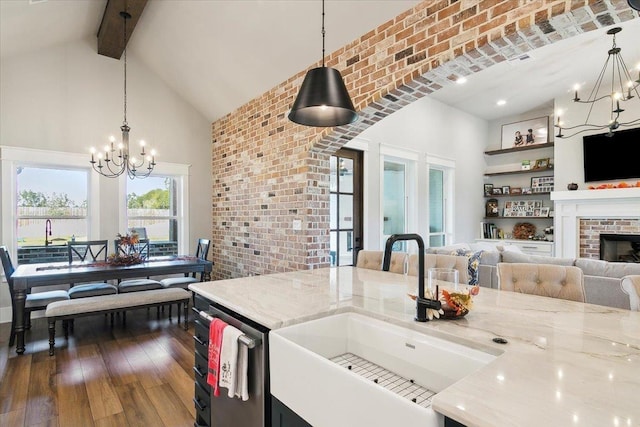 kitchen with light stone countertops, hanging light fixtures, a fireplace, and sink