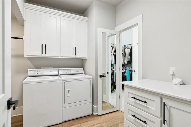 laundry area with cabinets, light wood-type flooring, and washing machine and clothes dryer