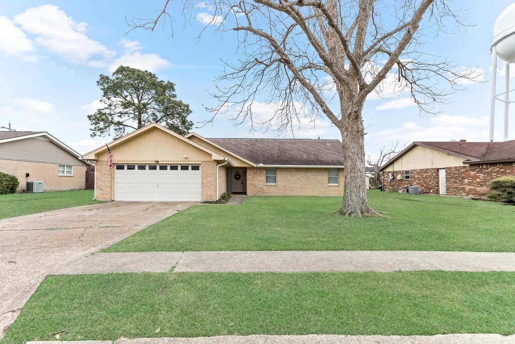 single story home featuring a garage, brick siding, concrete driveway, and a front lawn