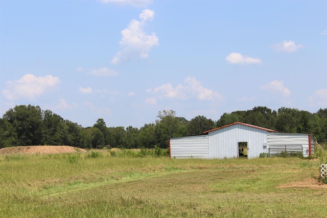 view of yard with a garage, an outbuilding, a pole building, and a view of trees