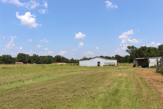 view of yard featuring a garage, a rural view, an outbuilding, and an outdoor structure