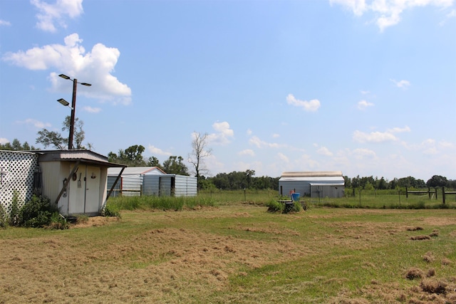 view of yard featuring a storage shed, fence, and an outbuilding