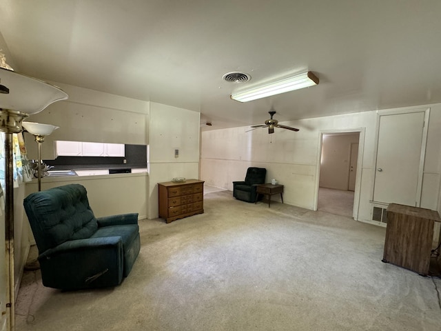 living area featuring light colored carpet and ceiling fan