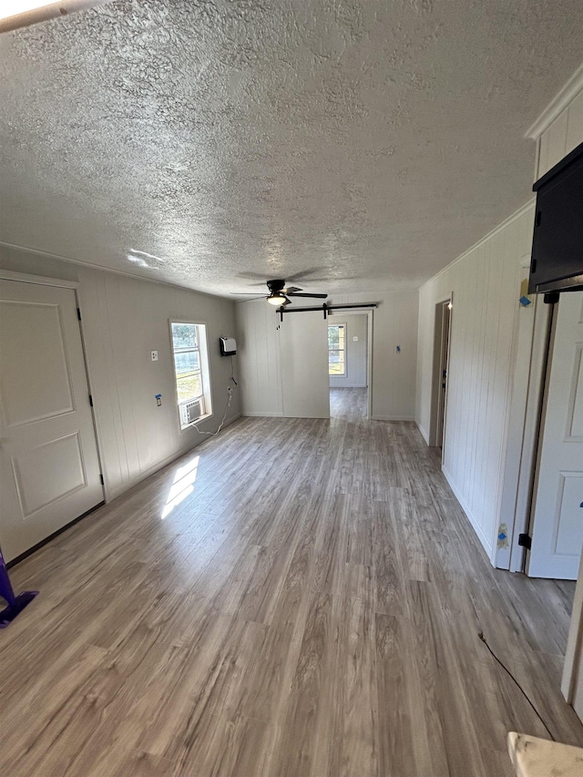 unfurnished living room with ceiling fan, a textured ceiling, and light wood-type flooring