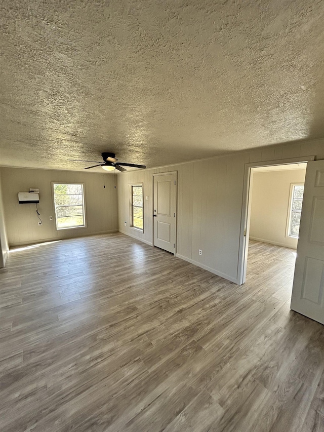 unfurnished living room featuring ceiling fan, hardwood / wood-style floors, and a textured ceiling