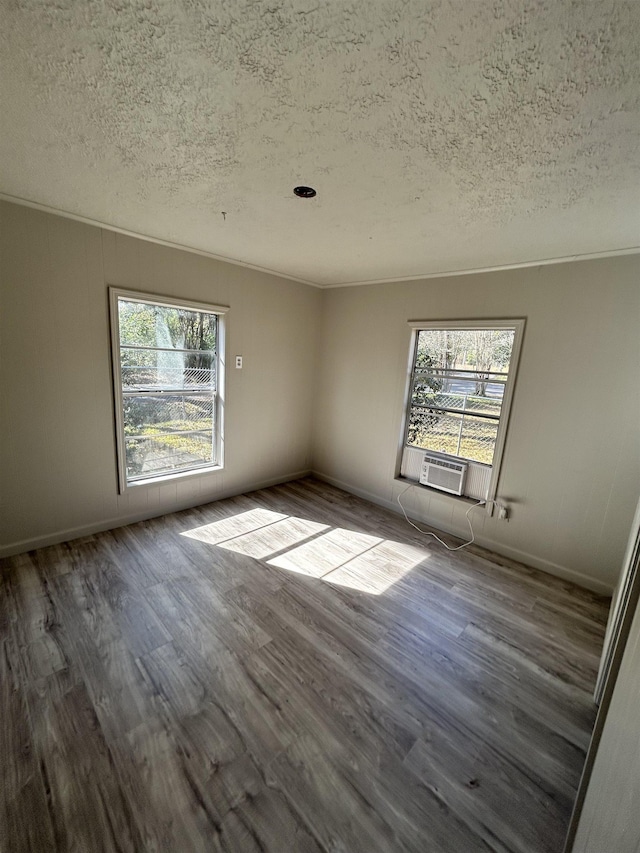 spare room with cooling unit, hardwood / wood-style floors, ornamental molding, and a textured ceiling