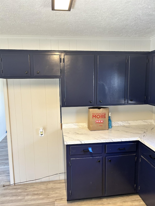 kitchen with light stone counters, a textured ceiling, and light wood-type flooring