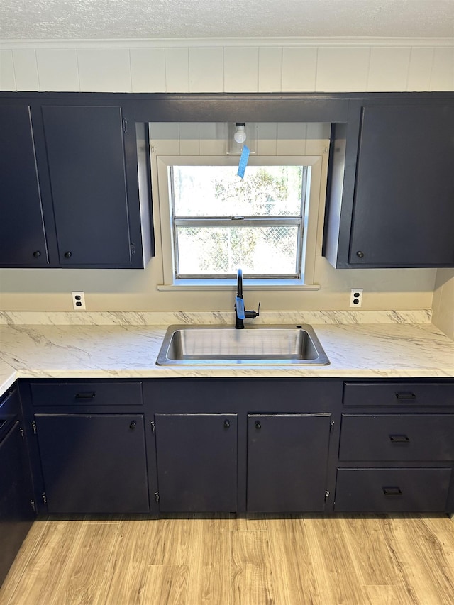 kitchen featuring crown molding, light hardwood / wood-style floors, sink, and a textured ceiling