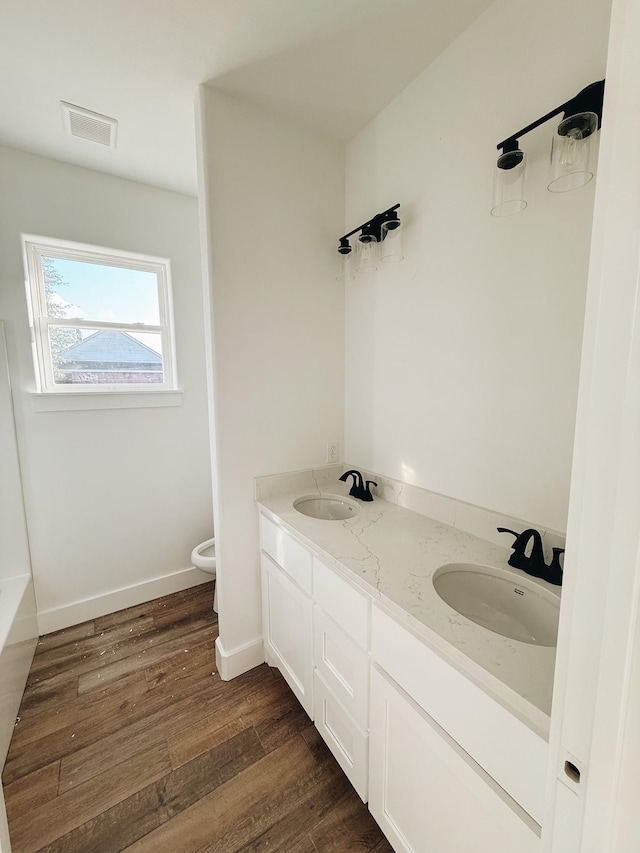 bathroom with a washtub, wood-type flooring, vanity, and toilet