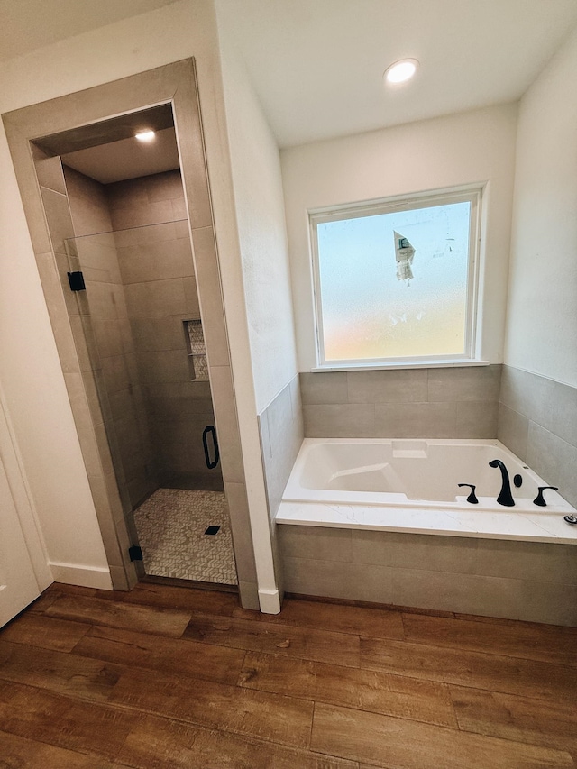 bathroom featuring wood-type flooring and shower with separate bathtub