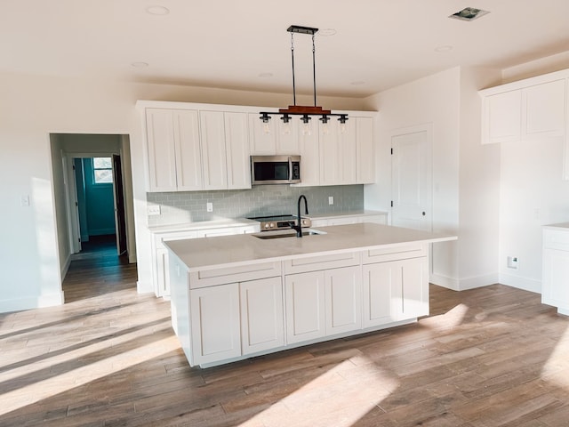 kitchen with sink, pendant lighting, a center island with sink, white cabinets, and appliances with stainless steel finishes