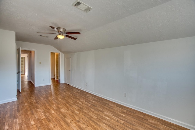 empty room featuring ceiling fan, a textured ceiling, lofted ceiling, and light wood-type flooring