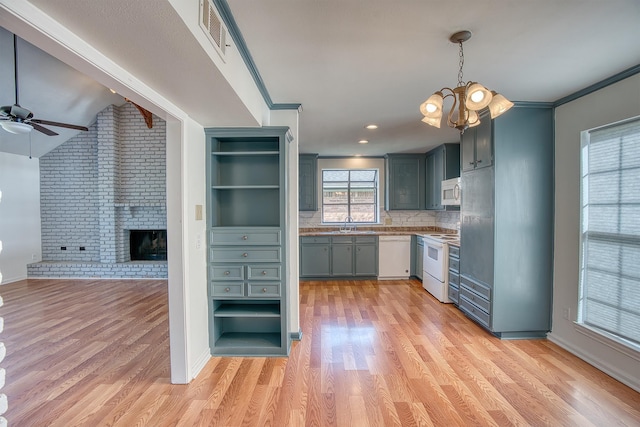 kitchen with tasteful backsplash, a fireplace, white appliances, hanging light fixtures, and ceiling fan with notable chandelier